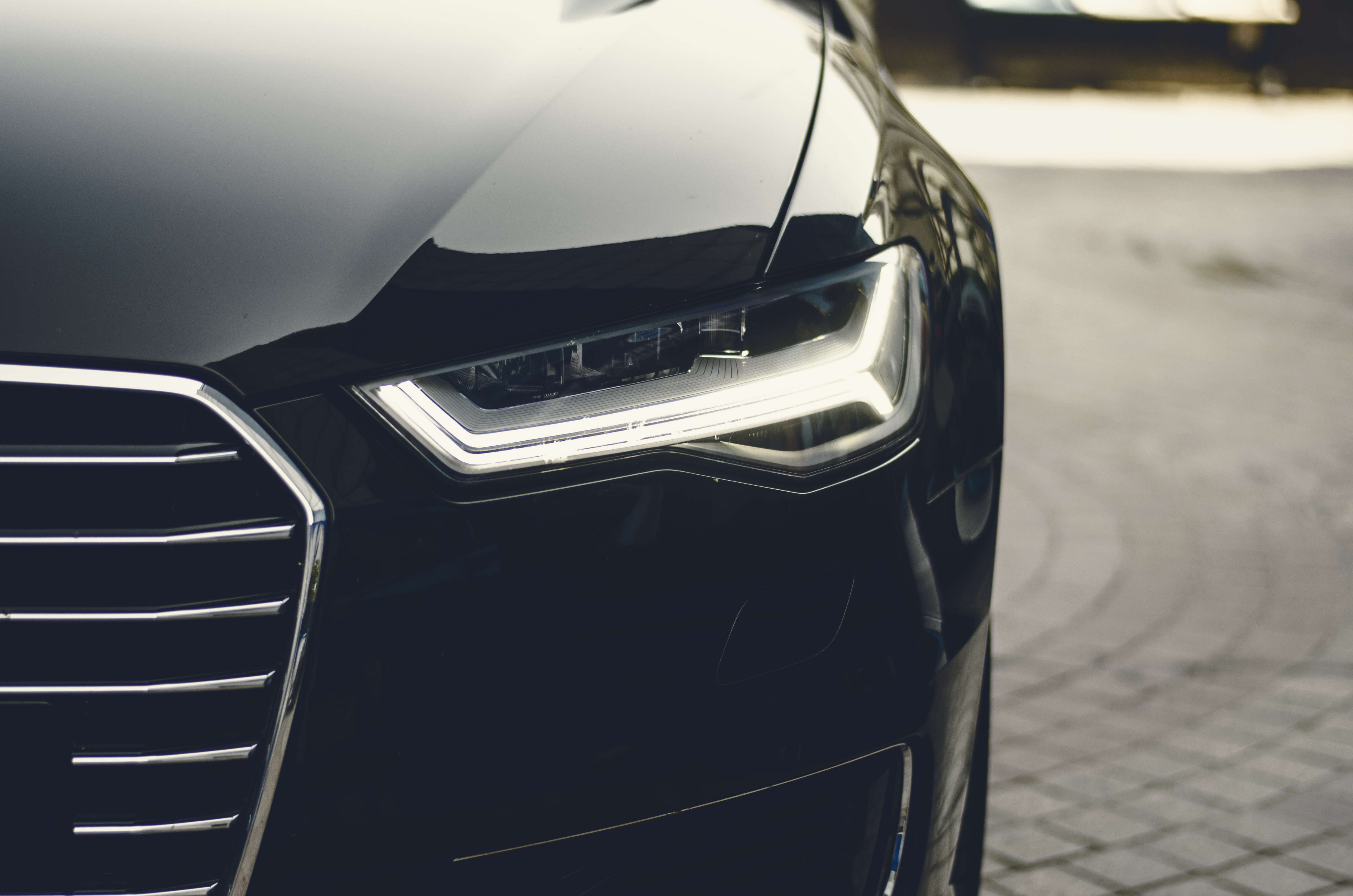 Close-up of a black Audi front headlight and grille
