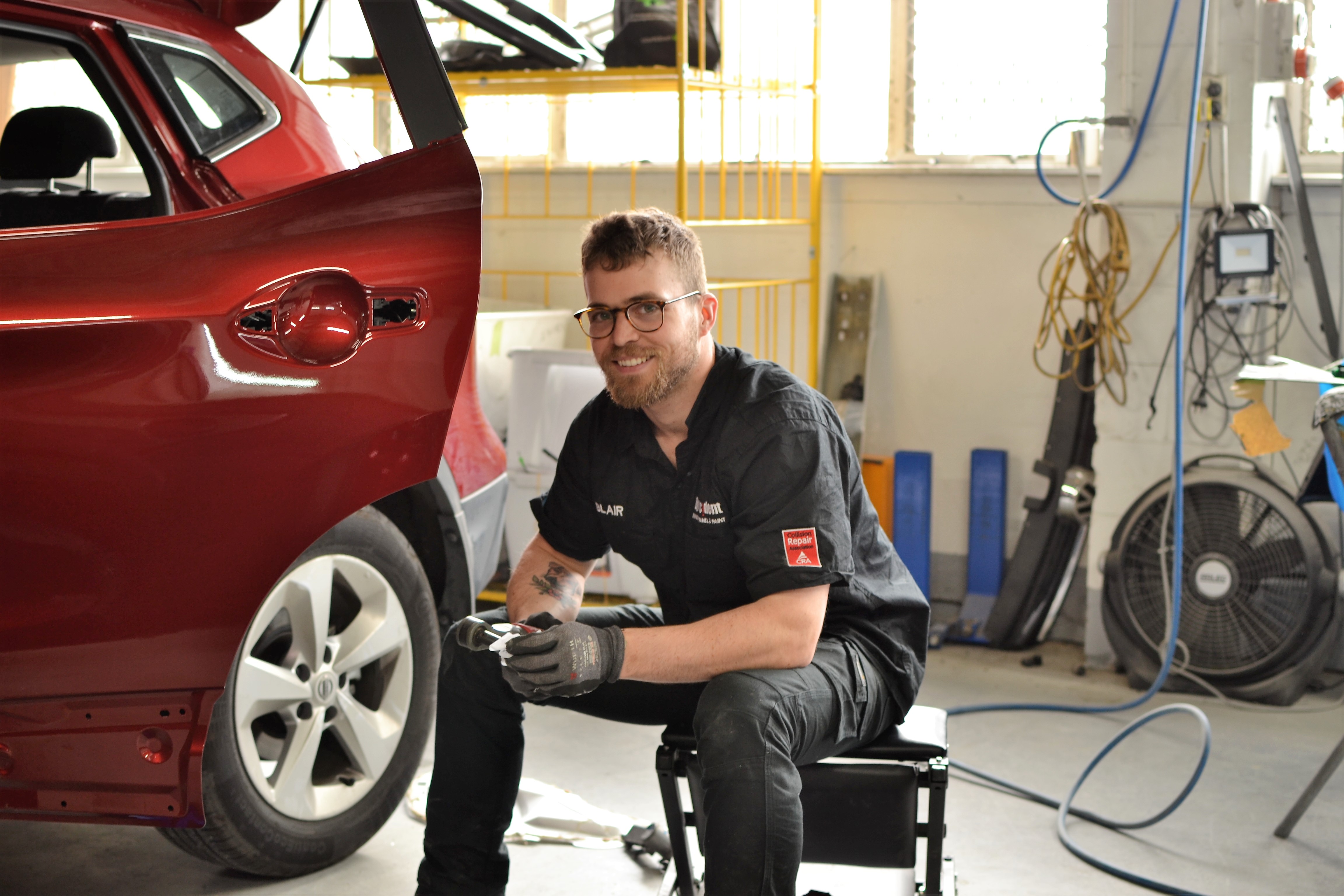 ByAccident technician Blair working on a red car in the Birkenhead workshop